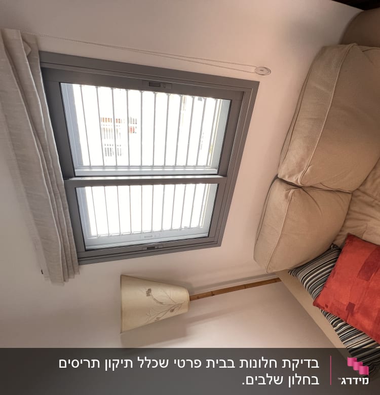 תריסים לבנים על חלון עם מסגרת אפורה
